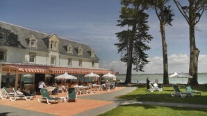 A hotel with outdoor seating and a view of the water.