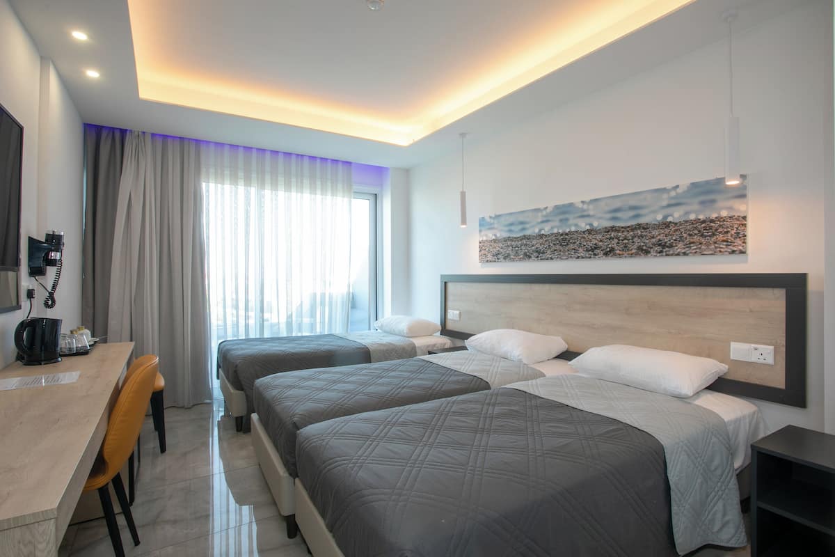 Quarto de hotel com duas camas, uma escrivaninha e uma cadeira.