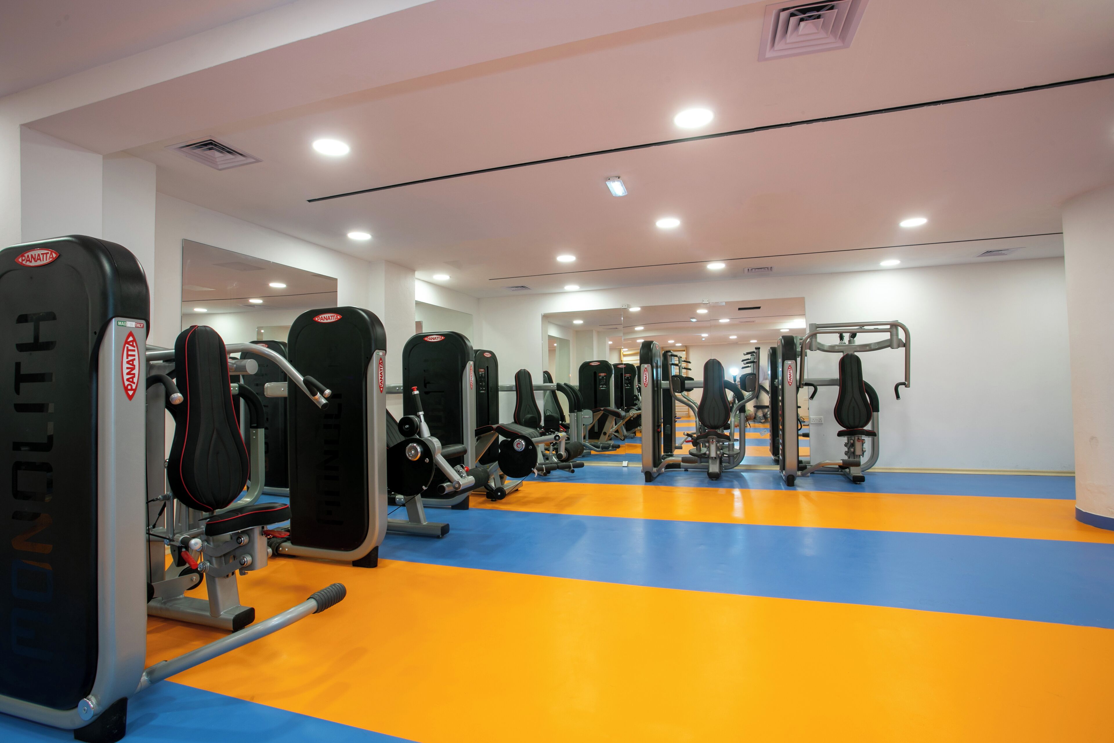 A gym with various exercise machines and a blue and orange floor.