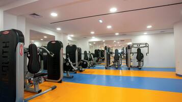 A gym with various exercise machines and a blue and orange floor.