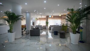 A spacious lobby with a marble floor, modern furniture, and potted plants. - Papouis Protaras Hotel (Paralimni)