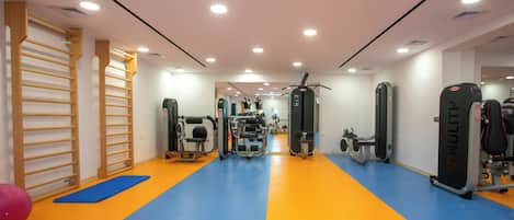 A gym with exercise equipment, wooden racks, and a blue and orange floor.