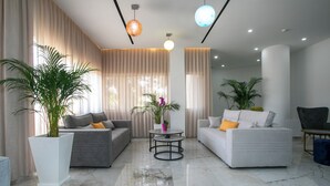 A modern living room with two sofas, a coffee table, and potted plants. - Papouis Protaras Hotel (Paralimni)