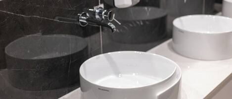 A bathroom with three sinks, a mirror, and a soap dispenser.