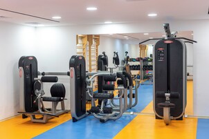 A gym with weight machines, benches, and a mirrored wall.
