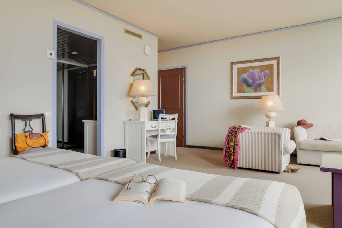 Ett hotellrum med en säng, ett skrivbord, en stol, en soffa och en dörr.