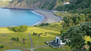 A coastal landscape with a beach, a small white building, and a path leading to it. - Pestana Bahia Praia Nature & Beach Resort (Vila Franca do Campo)