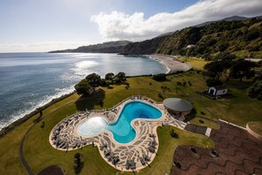 A resort with a large swimming pool, a beach, and a mountainous backdrop. - Pestana Bahia Praia Nature & Beach Resort (Vila Franca do Campo)