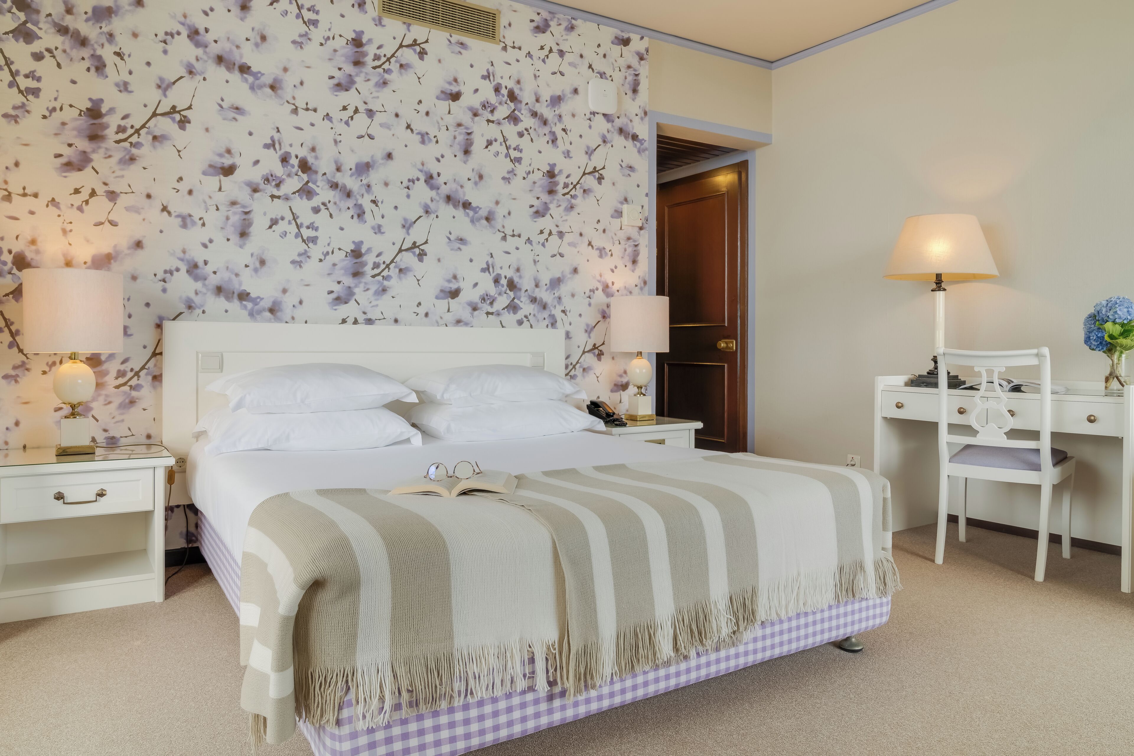A bedroom with a bed, nightstands, a desk, and a chair.