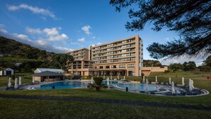 A multi-story hotel with a swimming pool, outdoor seating, and a landscaped garden. - Pestana Bahia Praia Nature & Beach Resort (Vila Franca do Campo)