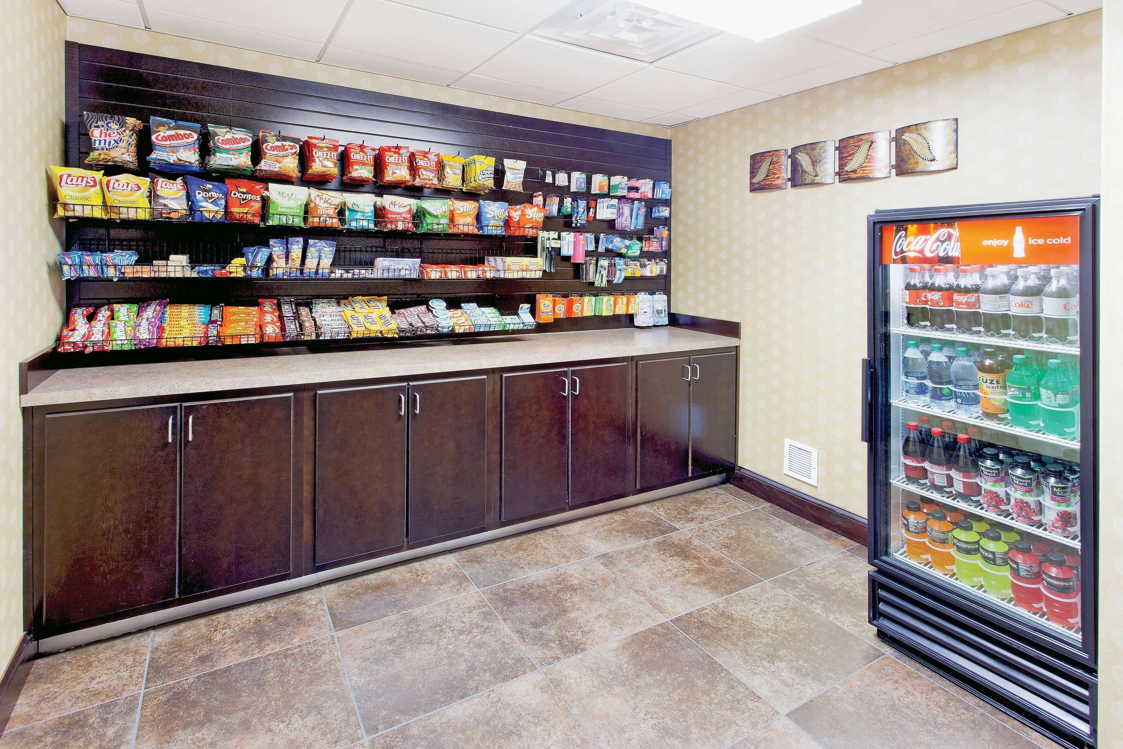 A snack display with various chips and snacks, a beverage refrigerator with multiple drink options, and a tiled floor.