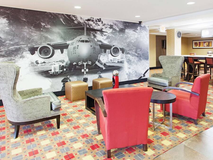 A hotel lobby with a large airplane mural, comfortable seating, and a patterned carpet.