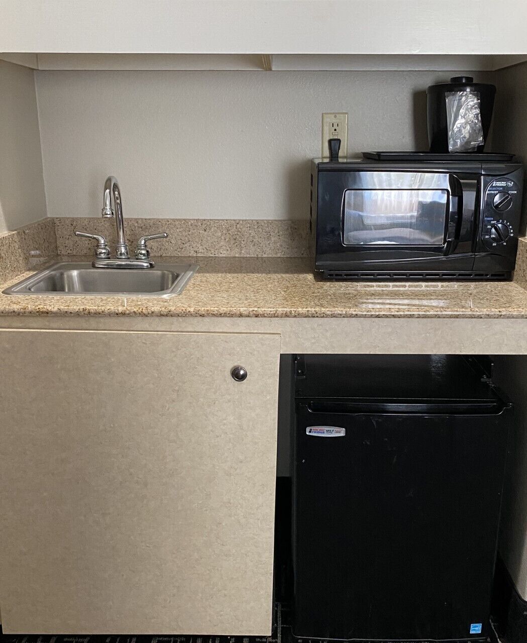 A compact kitchenette with a stainless steel sink, a black microwave, and a black dishwasher.