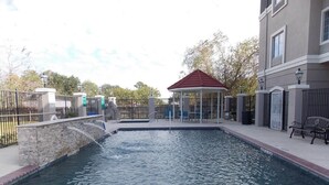 A swimming pool with a gazebo, surrounded by a fence and benches. - Quality Inn and Suites (Rosenberg)