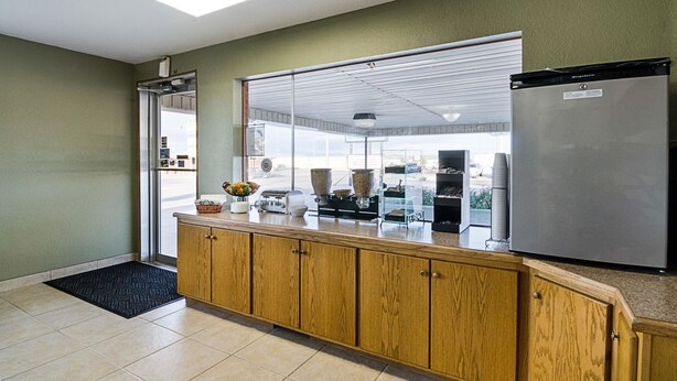 A kitchen with wooden cabinets, a stainless steel refrigerator, and a window with blinds.
