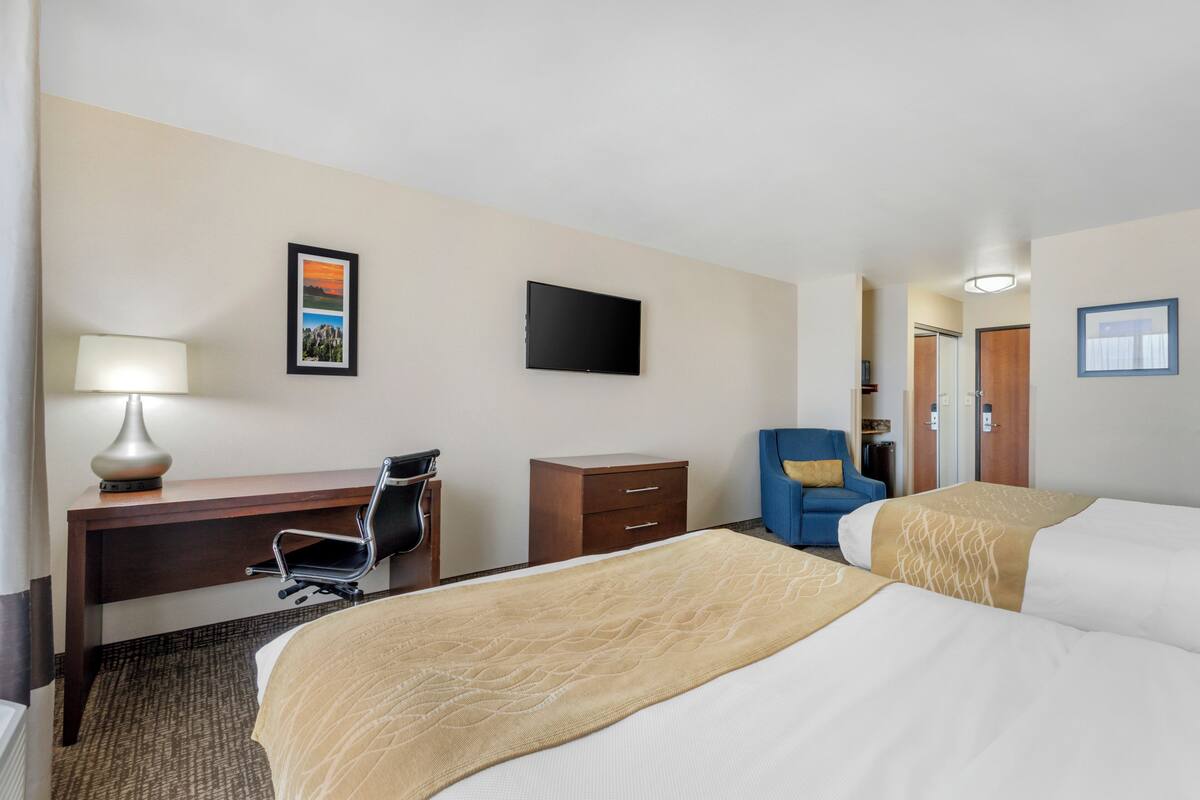 Ein Hotelzimmer mit Bett, Schreibtisch, Stuhl und Fernseher an der Wand.