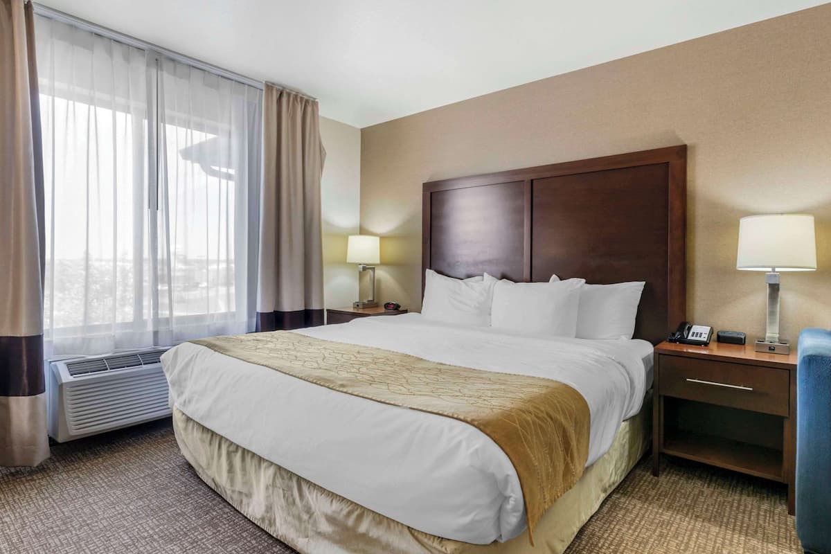 Ein Hotelzimmer mit einem großen Bett, einem Nachttisch mit Lampe, einem Beistelltisch und einem Sessel.