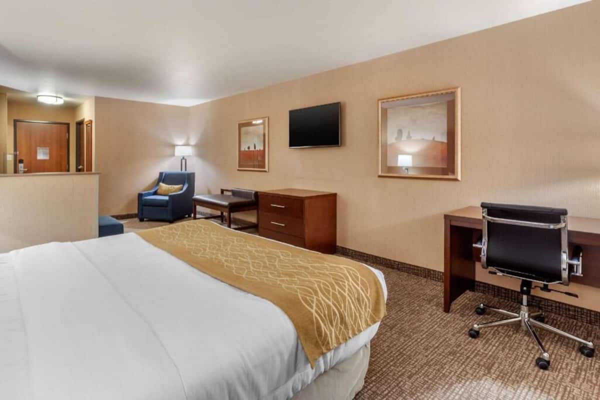 Ein Hotelzimmer mit Bett, Schreibtisch, Stuhl, Fernseher und Bildern an der Wand.