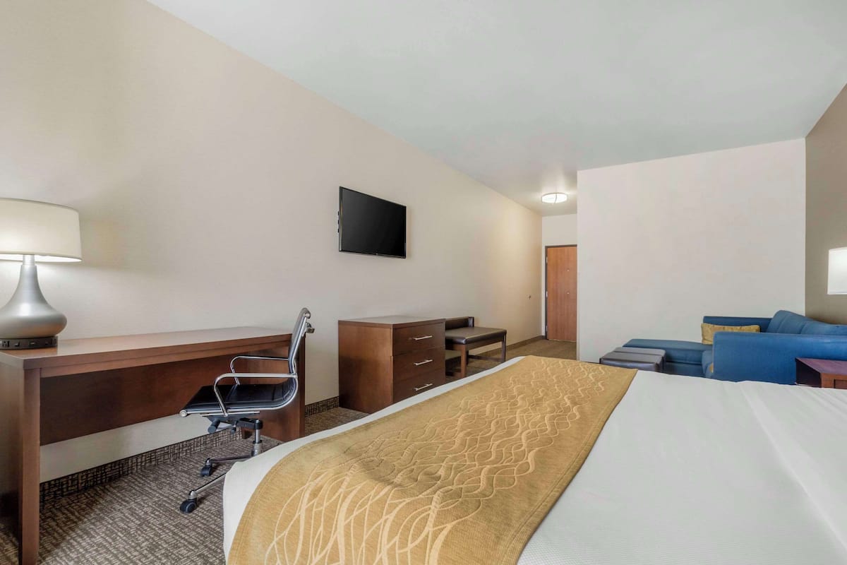 Ein Hotelzimmer mit Bett, Schreibtisch, Stuhl und einem Fernseher an der Wand.