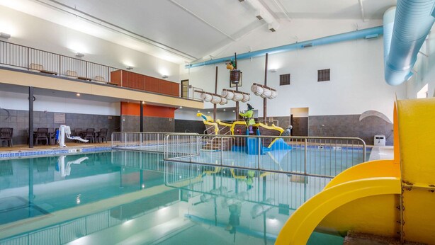 Una gran piscina interior con un trampolín y un tobogán.