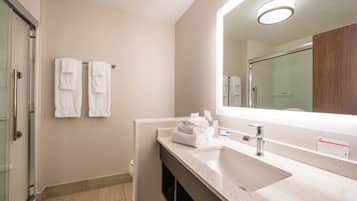 A modern bathroom with a large mirror, a sink, and two towels hanging on the wall.