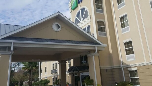 Un bâtiment de l’hôtel Holiday Inn Express, avec une façade beige, une enseigne bien visible et un espace d’entrée abrité.