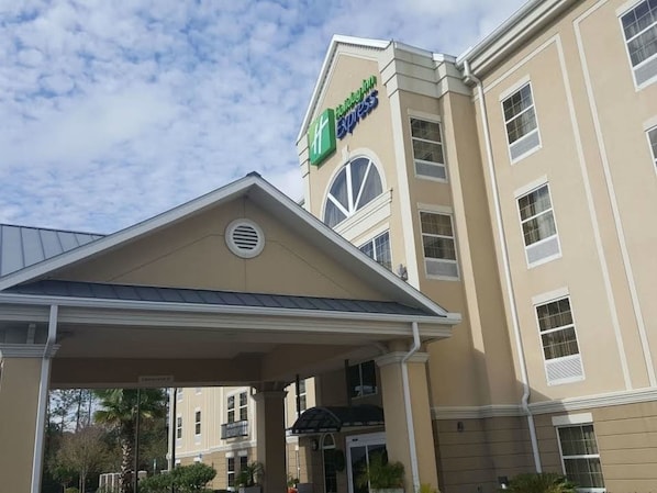 Edificio de Holiday Inn Express con fachada color crema, un cartel llamativo y un área de entrada cubierta.