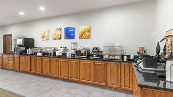 A modern kitchen with wooden cabinets, a coffee station, and a microwave.