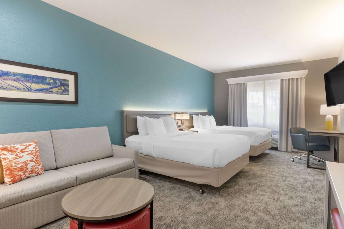 Habitación de hotel con dos camas, un sofá, un escritorio y un televisor.