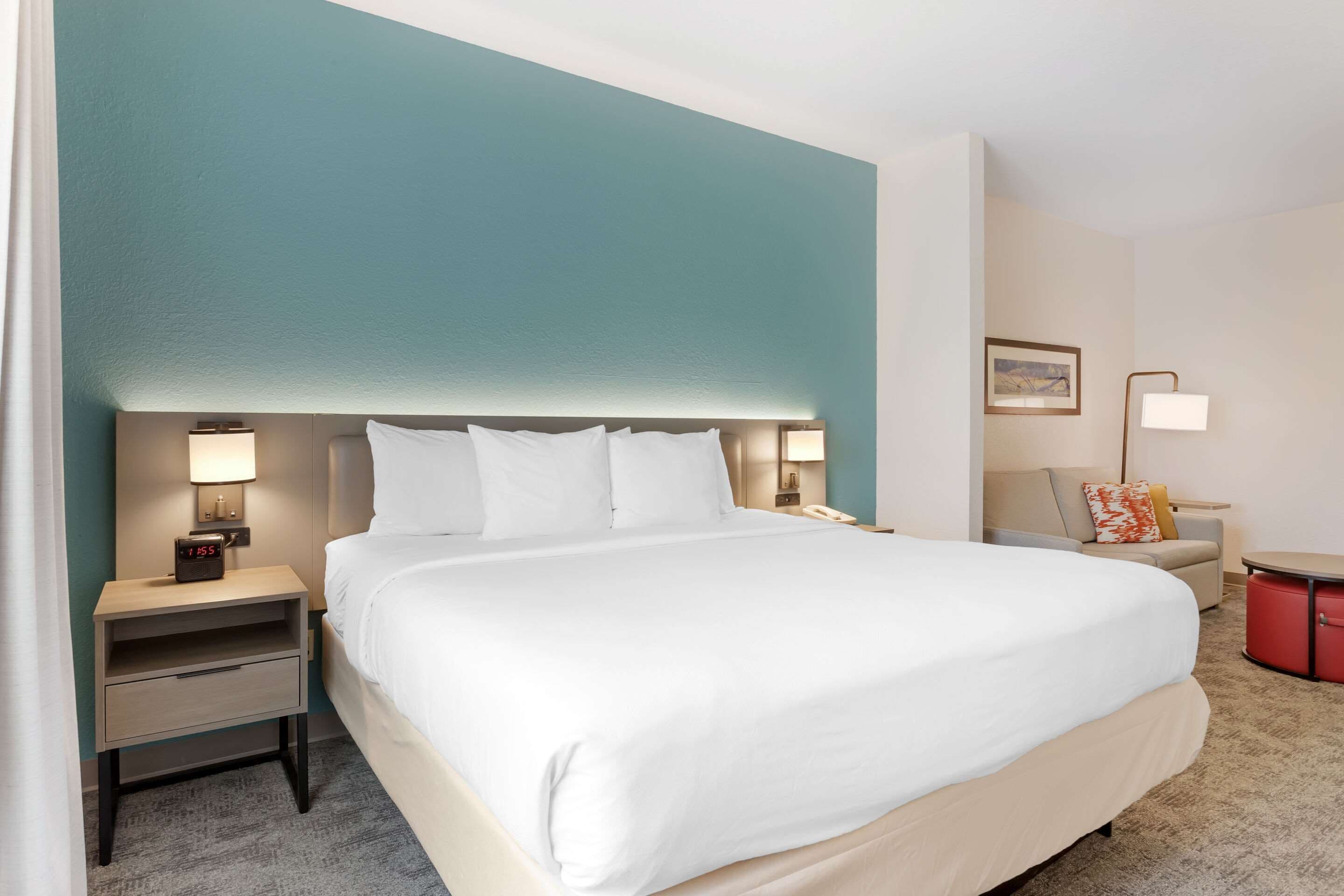 Ein Hotelzimmer mit einem großen Bett, einem Nachttisch mit Lampe, einem kleinen Tisch und einem roten Schrank.