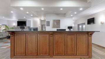 A reception area with a wooden counter, a flat-screen TV, and a wall-mounted clock.