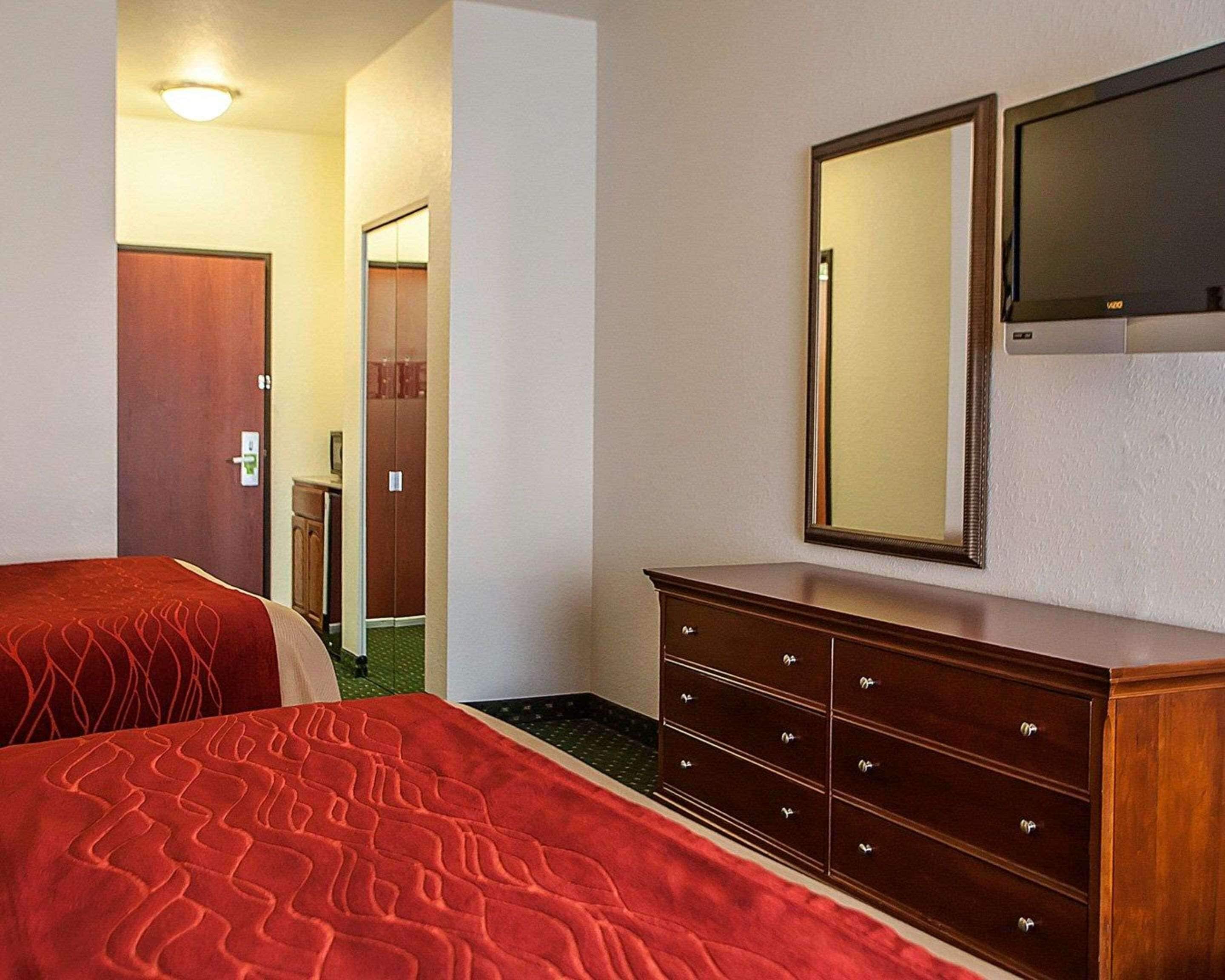 A hotel room with a bed, a dresser, a mirror, and a television.