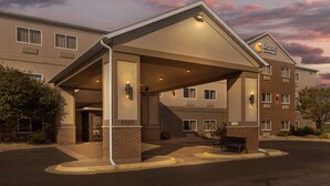 Un hôtel doté d’une entrée couverte, d’une façade en briques et d’une enseigne indiquant « Comfort Suites ».