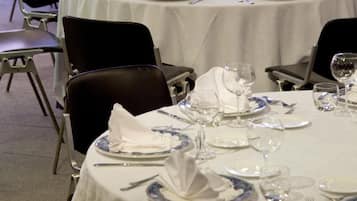 Un comedor con mesas redondas dispuestas para varios invitados, cada una con manteles blancos y platos azul y blanco.