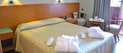 A hotel room with a large bed, two bedside lamps, a small table with breakfast items, and a chair.
