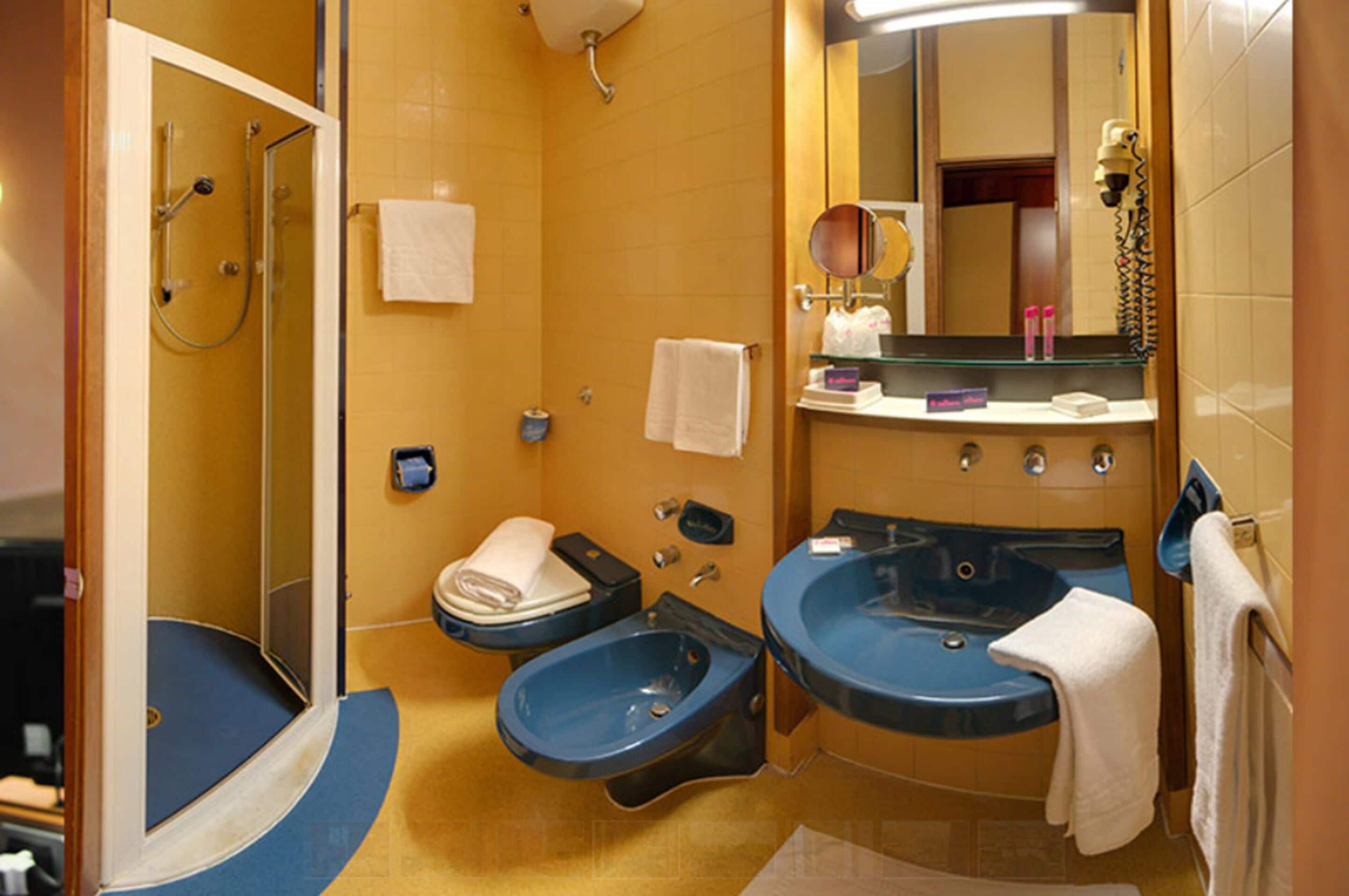 Un baño con ducha, dos lavamanos, bañera y espejo.