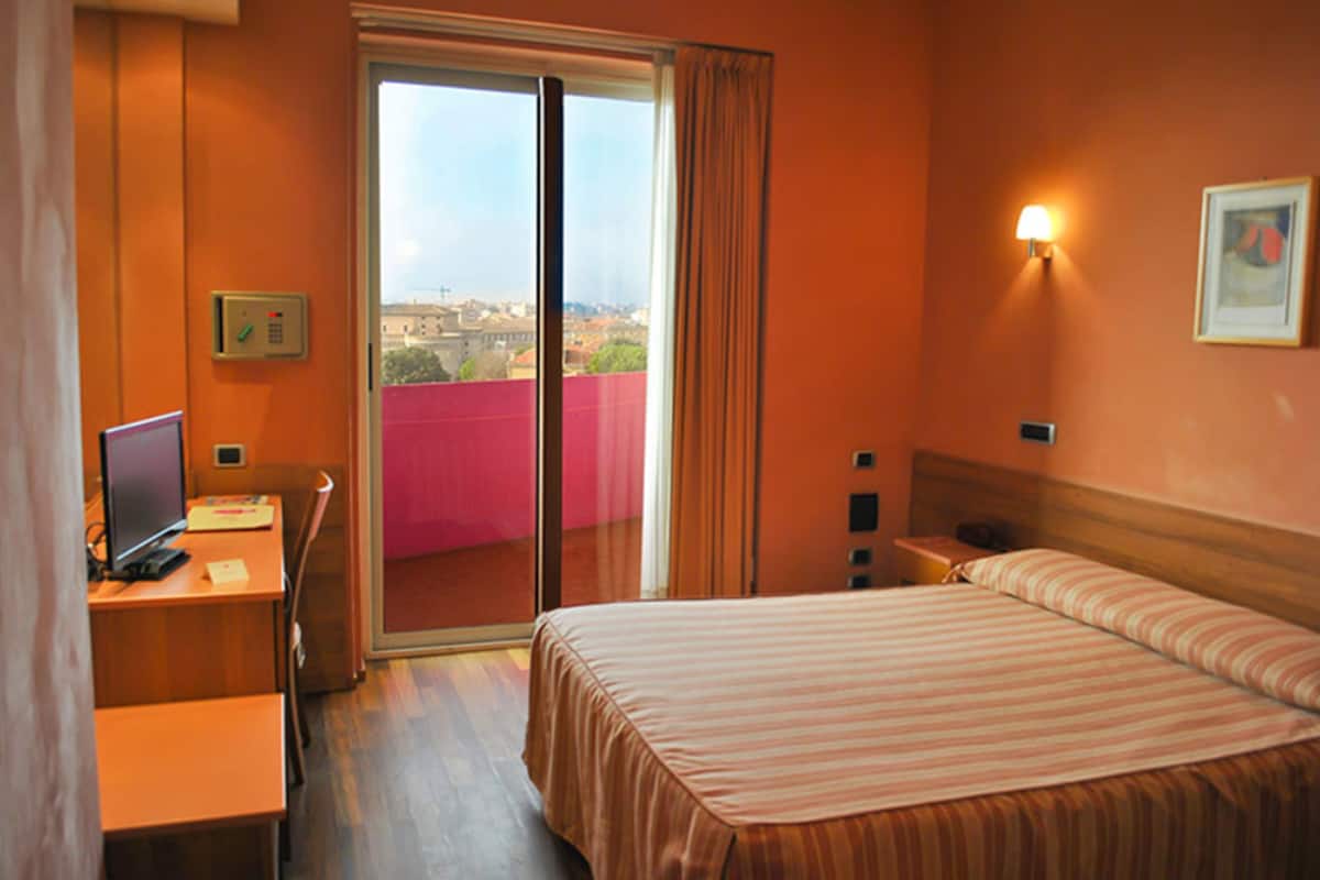 Habitación de hotel con cama, escritorio y ordenador.