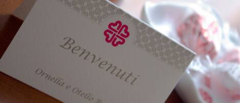 A white card with "Benvenuti" and "Ornella e Oresto Baldini" printed on it.
