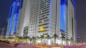 Ein hoch aufragendes Hotel mit modernem Design, das durch eine markante Eckbebauung und blau beleuchtete Linien, welche die Architektur hervorheben, besticht.