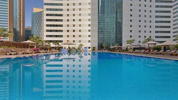 Una piscina al aire libre, sombrillas, sillones reclinables de piscina