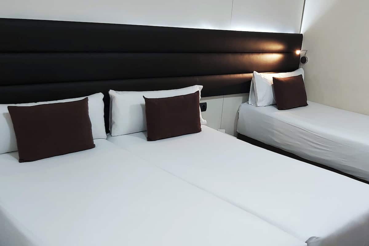 Una habitación de hotel con una cama grande, dos mesitas de noche y un cabecero.