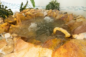 A hot spring with clear water surrounded by rocks and plants. - Huinid Bustillo Hotel & Spa (San Carlos de Bariloche)