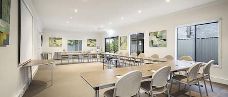 A conference room with a long table, multiple chairs, and a projector screen.