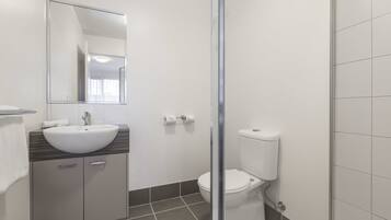 Ein modernes Badezimmer mit Waschbecken, Spiegel, Toilette und Duschbereich.