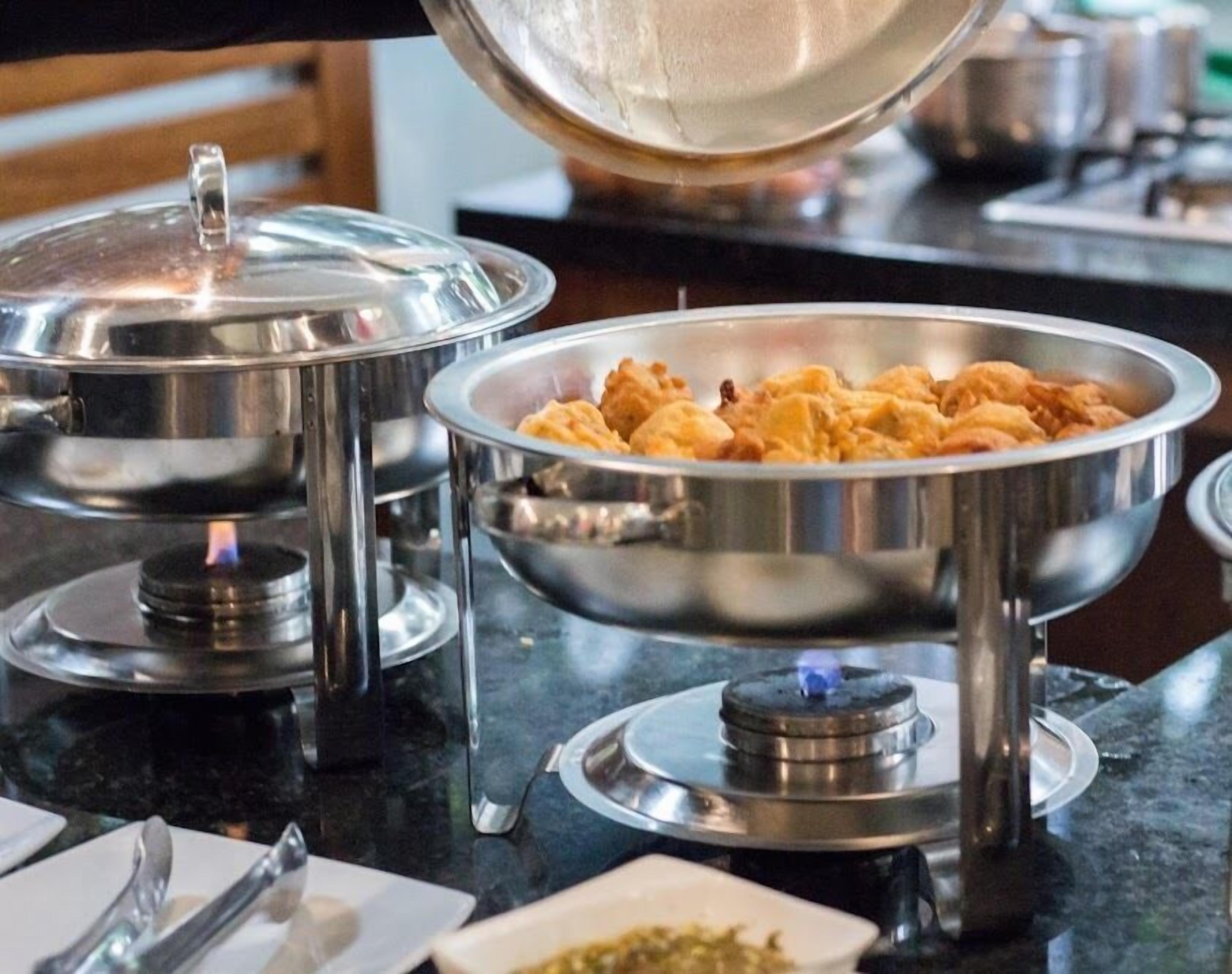 Mesa de buffet con recipientes tapados y una estufa a gas.