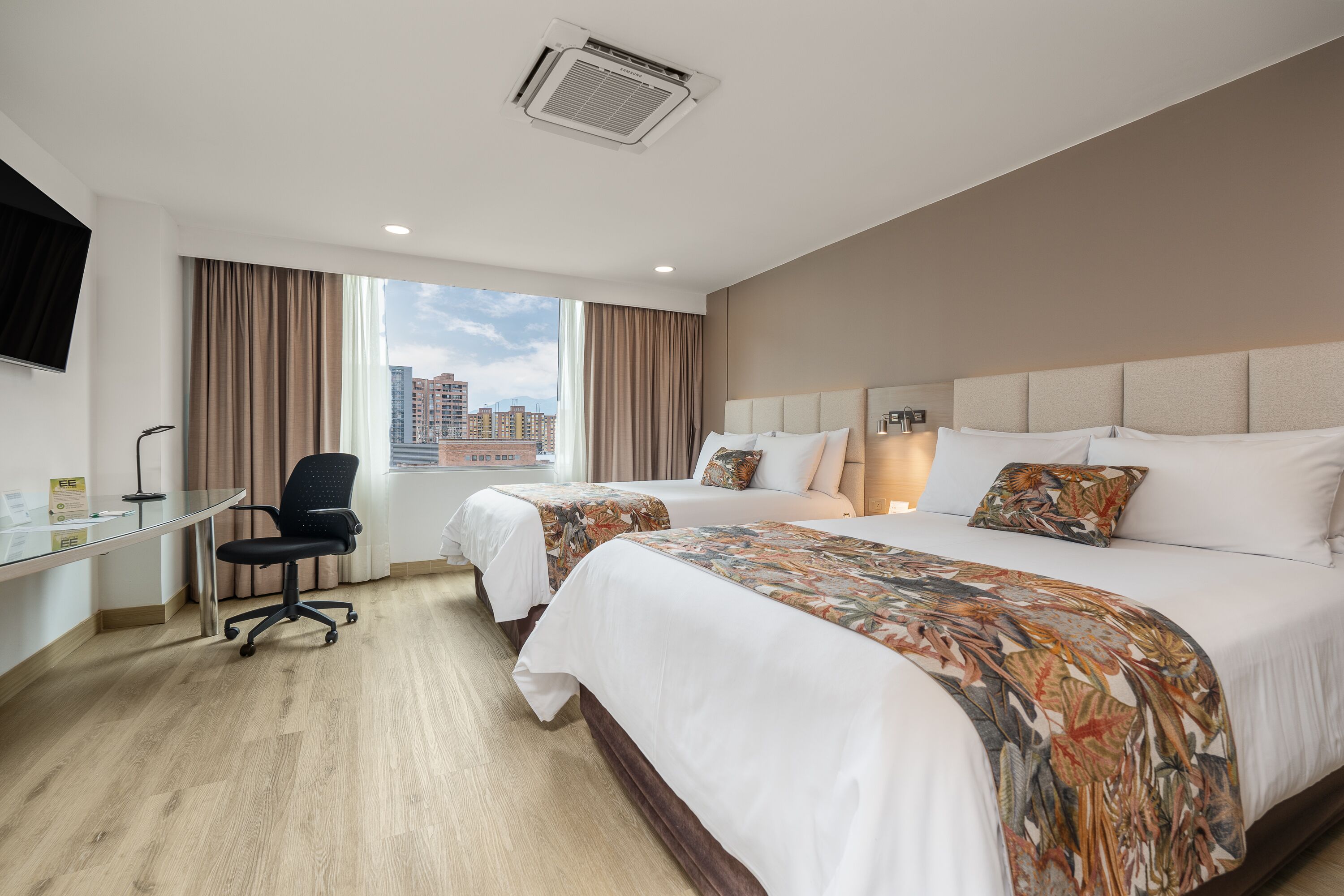 Ein Hotelzimmer mit zwei Betten, einem Schreibtisch und einem Stuhl.