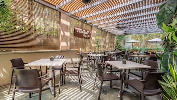 An outdoor cafe with wooden slatted walls, tables, and chairs.