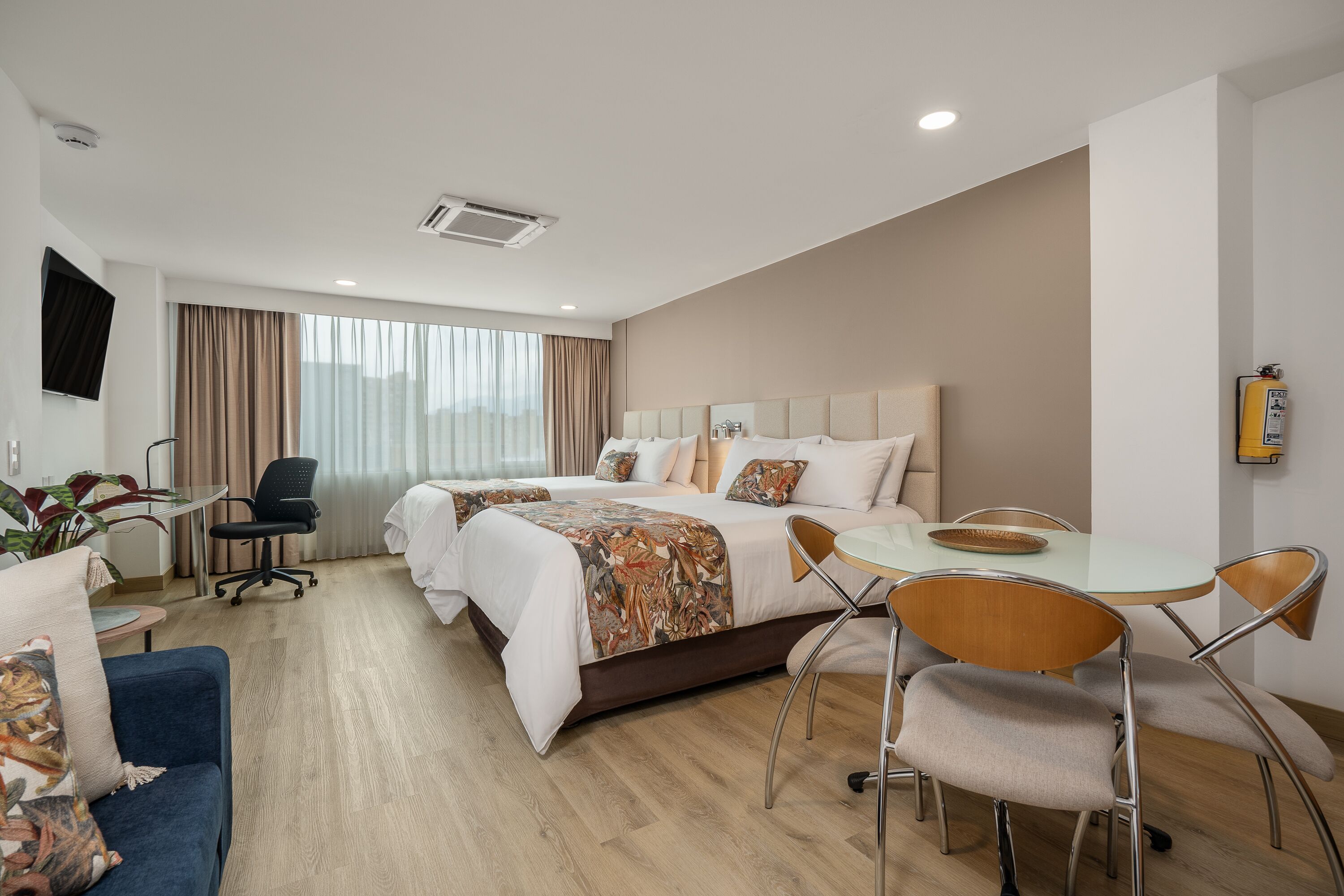 Una habitación de hotel con cama, escritorio, silla, mesa y televisor.