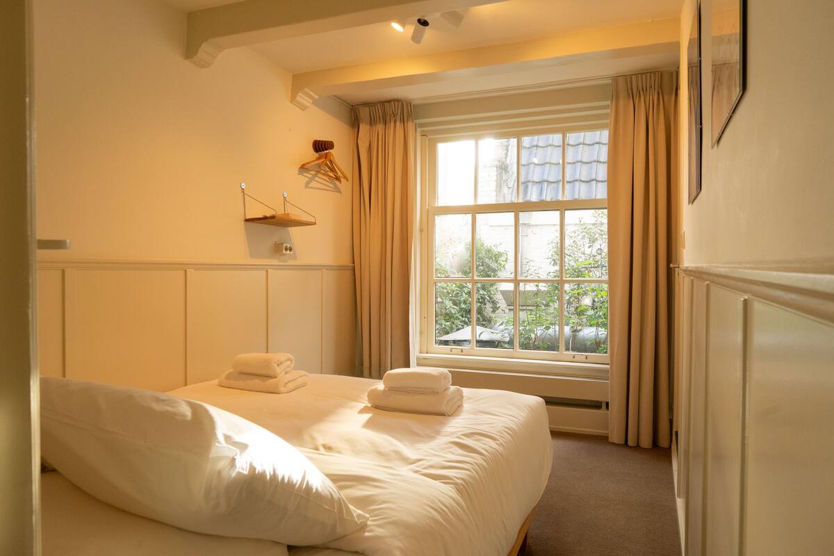 A bedroom with a large bed, a window with curtains, and a radiator.