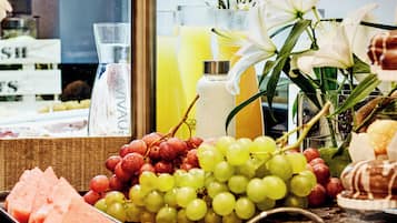 A display of fresh fruits and beverages, including grapes, watermelon, and a variety of juices.